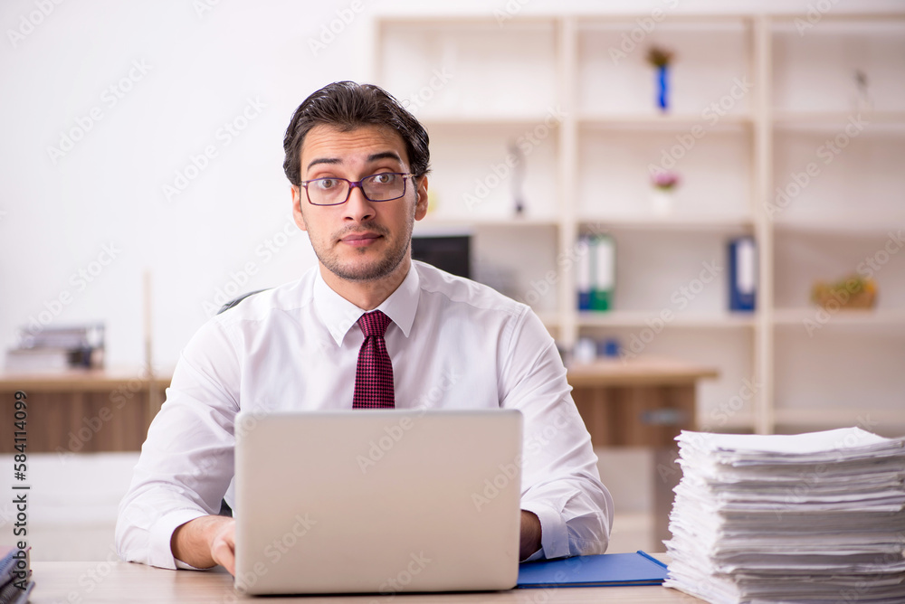 Young male employee and too much work in the office Young male employee and too much work in the office