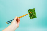Young woman holding nori seaweed with wooden chopsticks. japanese traditional cuisine