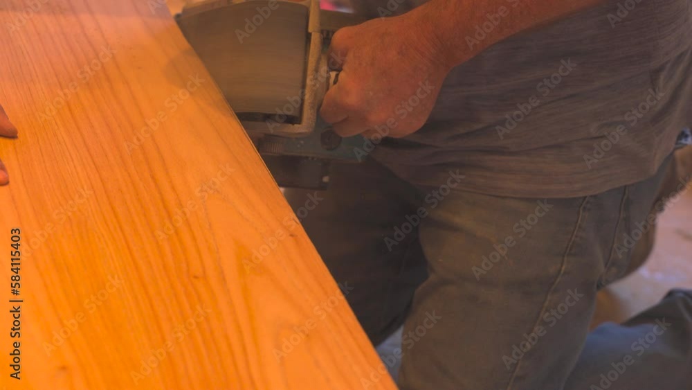 Tracking shot of male worker sanding wooden table on electric sander, close up Tracking shot of male worker sanding wooden table on electric sander, close up