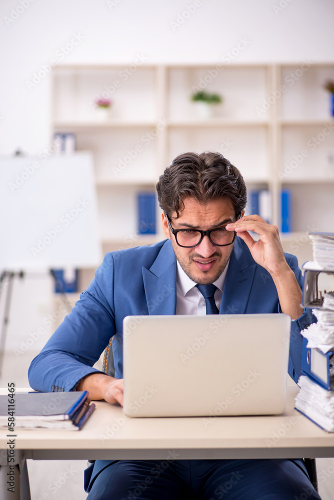 Young male employee and too much work in the office Young male employee and too much work in the office