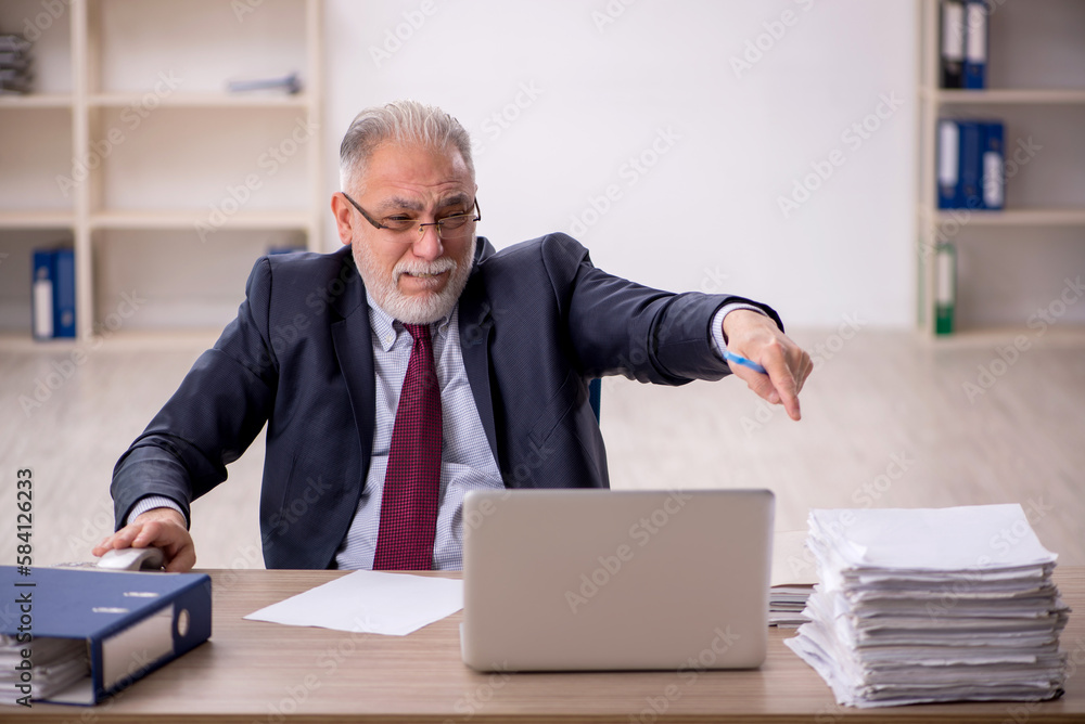 Old male employee sitting at workplace Old male employee sitting at workplace