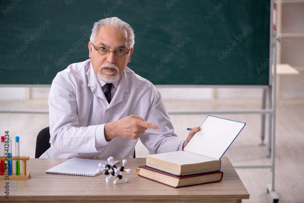 Old male chemistry teacher in the classroom Old male chemistry teacher in the classroom