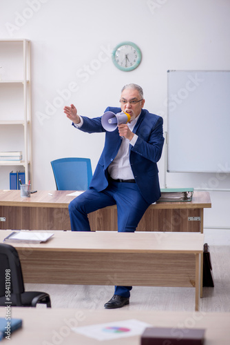 Old male teacher holding megaphone in the classroom