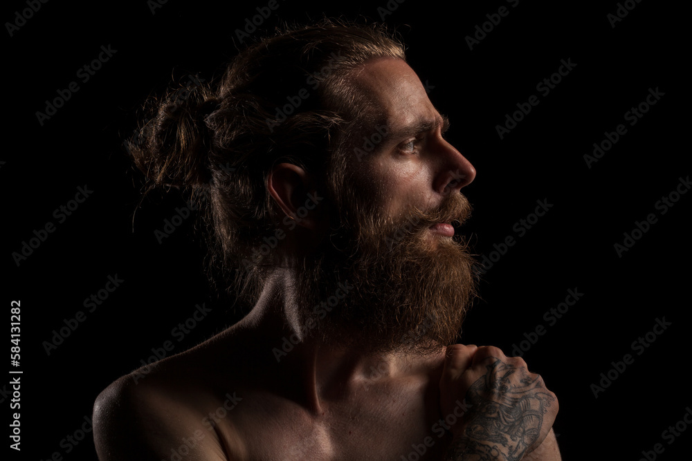Portrait of cool tattooed bearded hipster guy on black background in studio photo. Expression and fashion Portrait of cool tattooed bearded hipster guy on black background in studio photo. Expression and fashion