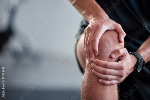Hands, knee and pain with a sports man holding a joint injury while training in a gym for health. Fitness, accident and anatomy with a male athlete suffering from an injured body during exercise
