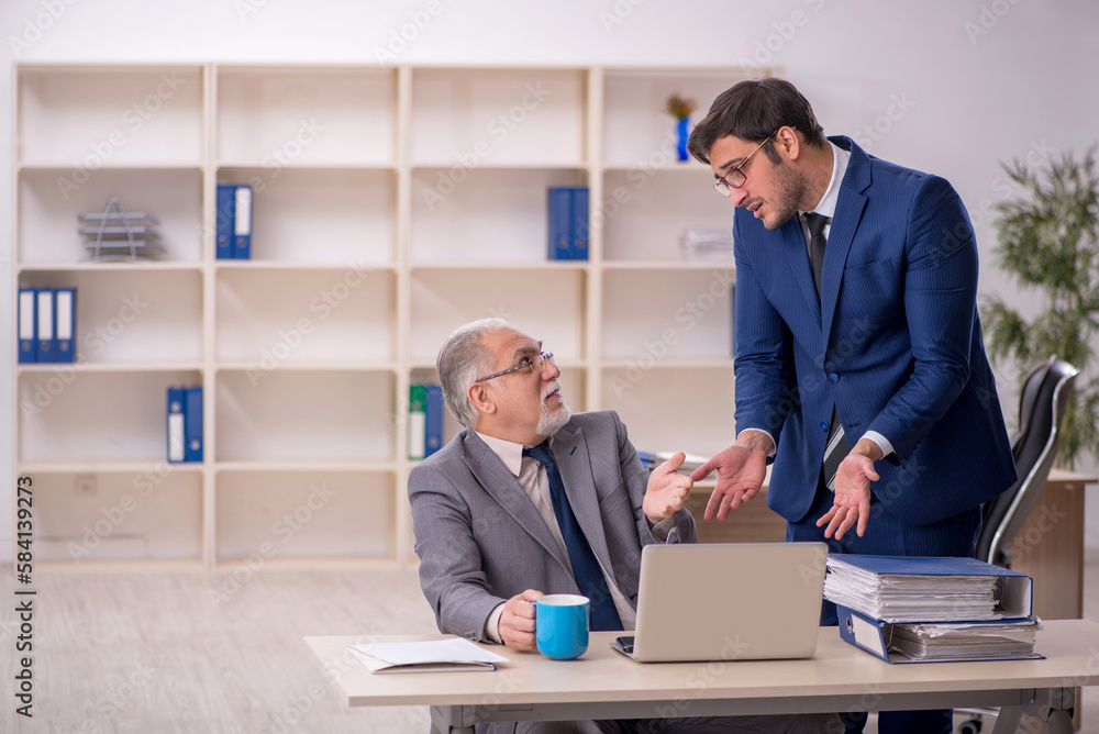 Old male boss and young male employee in the office Old male boss and young male employee in the office