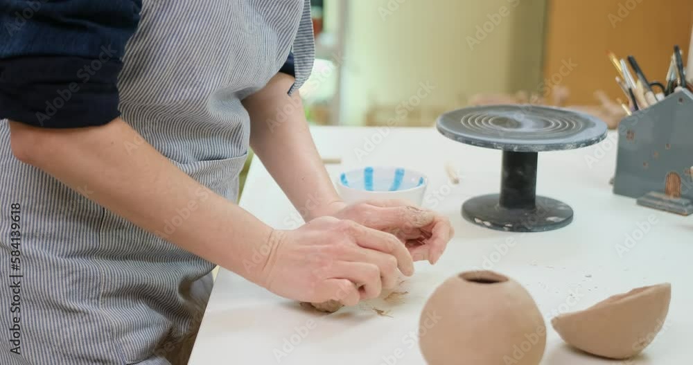 Closeup hands of ceramic artist wedging clay on a desk in art studio Closeup hands of ceramic artist wedging clay on a desk in art studio