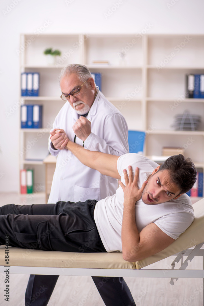 Fototapeta premium Young male doctor visiting old doctor chiropractor