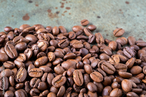 Close-up of roasted coffee beans on a green surface as a background. Selective focus.