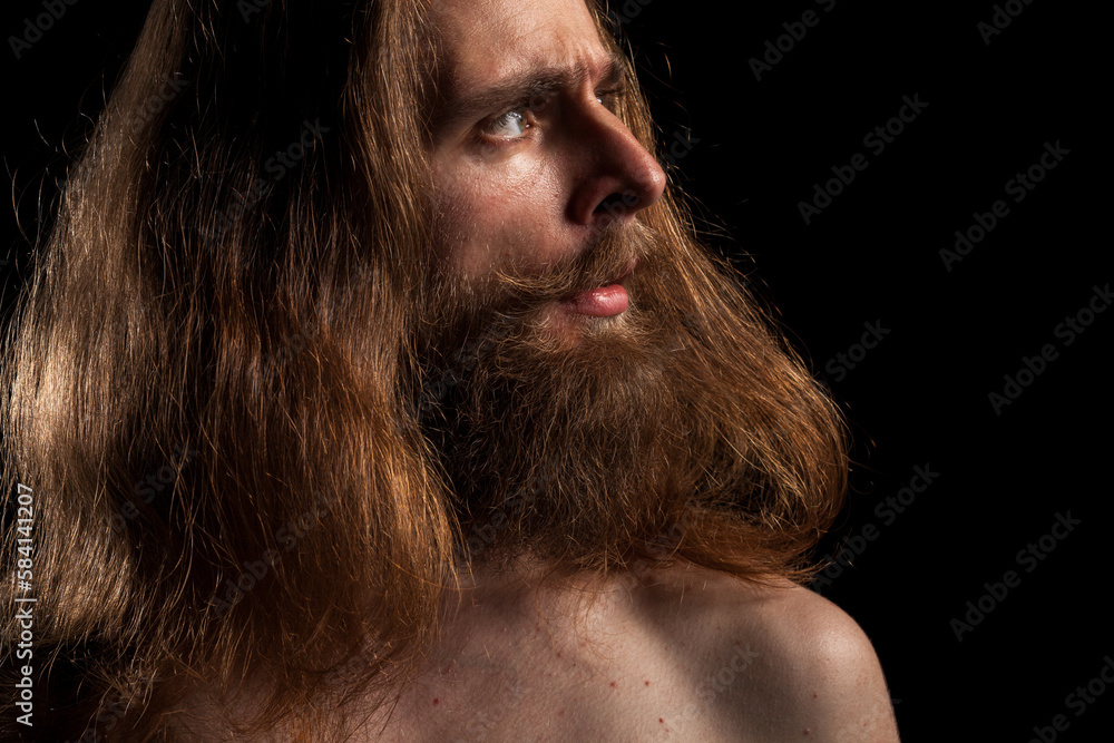 Cool looking tattooed bearded hipster on black background in studio photo. Expression and fashion