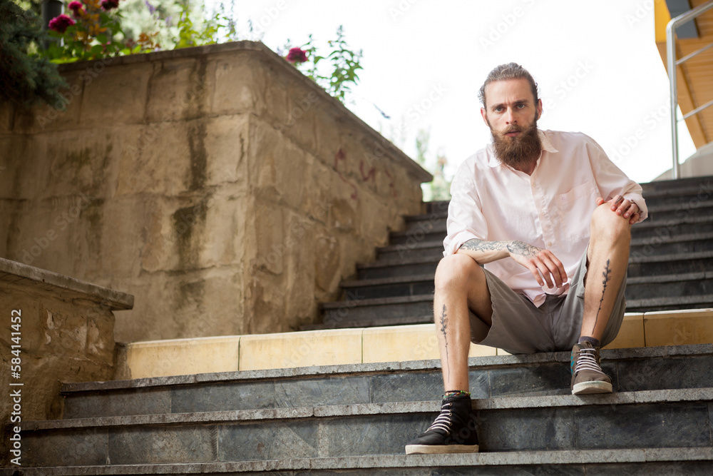Tattoed and bearded guy posing outdoor in the city Tattoed and bearded guy posing outdoor in the city
