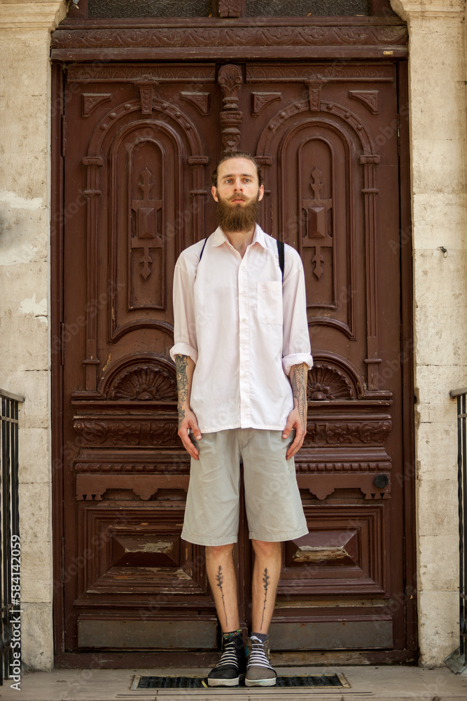 Hipster in white shirt posing in front of a door outside in the city. Style and diversity