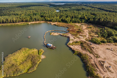 aerial view on crane extracts minerals from bottom onto huge barge in middle of lake or sea photo