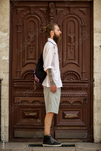 Hipster in white shirt posing in front of a door outside in the city. Style and diversity © DC Studio