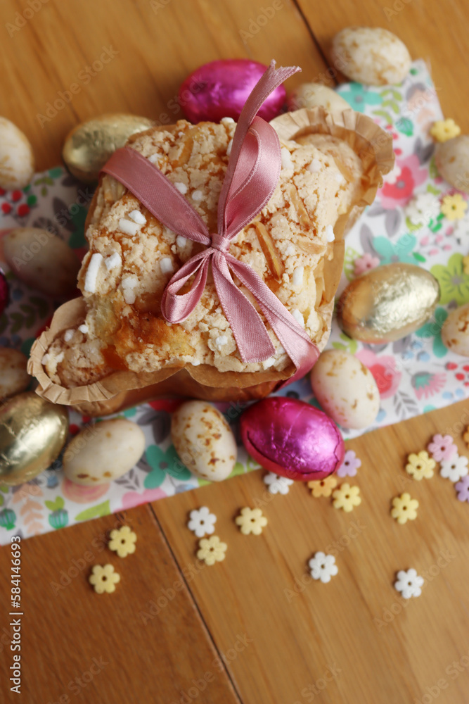 Colomba Pasquale. Sweet Easter cake with chocolate eggs on floral fabric . Italian traditional pastry on wooden table Colomba Pasquale. Sweet Easter cake with chocolate eggs on floral fabric . Italian traditional pastry on wooden table