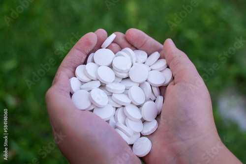 A handful of white round pills in his hands. Medications. Pills.
