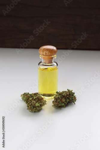 Glass bottle with herbal organic medicine CBD oil and medical cannabis bud on white background.