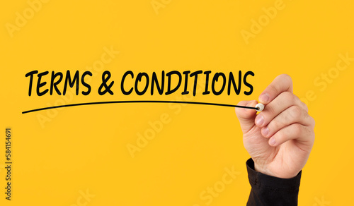 Terms and conditions business agreement and contract concept. Male hand draws a line under the handwritten word terms and conditions on yellow background.