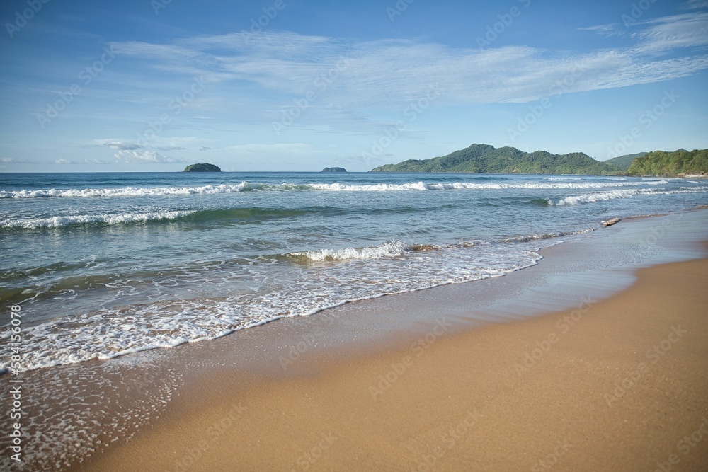 Dreamlike idyllic beach of El Nideo, Palawan in the Philippines with green hills in the background.