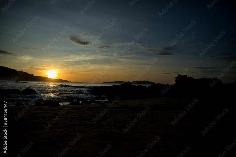 Fototapeta premium Picturesque sunset on the beach of El Nido, Palawan in the Philippines, the whole sky glows in golden yellow colors, hills on the horizon.