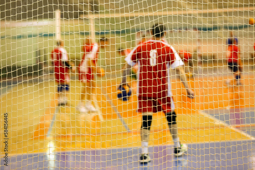 Blurry sports background. Net on the volleyball court, behind the net volleyball athletes