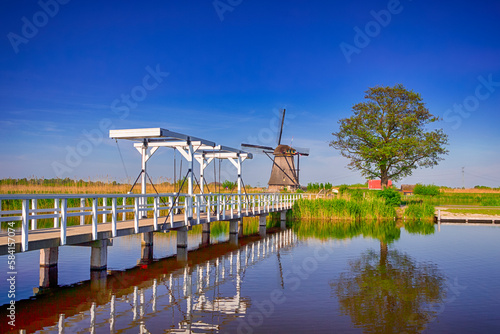 Wooden bridge across a canal and traditional windmill, Kinderdijk, Holland