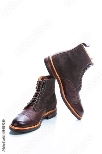 Footwear Ideas. Premium Dark Brown Grain Brogue Derby Boots Made of Calf Leather with Rubber Sole Placed on One Another Over White Background.