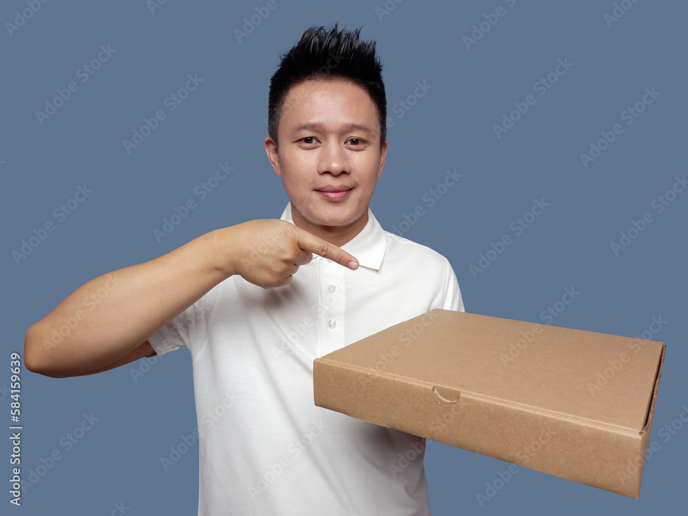 Man holding cardboard box and pointing isolated on plain background Man holding cardboard box and pointing isolated on plain background