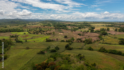 Tropical landscape: Agricultural land with plantings against a background of mountains and blue sky. Philippines.