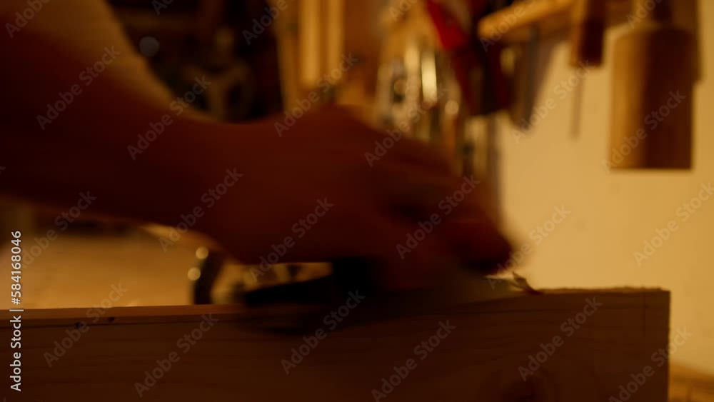 Close-up of a wooden board being sanded while shavings are coming off the board Close-up of a wooden board being sanded while shavings are coming off the board