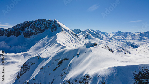 Alpine ski slope mountain winter panorama with ski lift,skiers and snow covered forest. © Aniwat