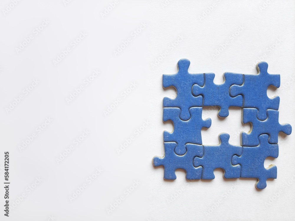 Pieces of a jigsaw puzzle with one missing piece in the center on a white background that illustrates teamwork and problem-solving. Puzzle day background Pieces of a jigsaw puzzle with one missing piece in the center on a white background that illustrates teamwork and problem-solving. Puzzle day background