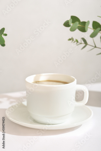 espresso coffee in a white classic cup, vertical, good morning, green leaves around a cup