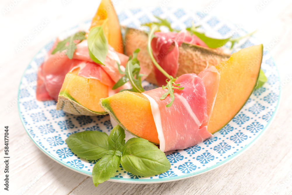 Sliced melon with ham and basil leaves
