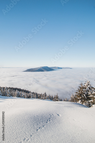 Mountainsides of the Beskydy region in the Czech Republic are sinking into a thick white inversion rising from the cities. Winter fairytale scenery in central Europe