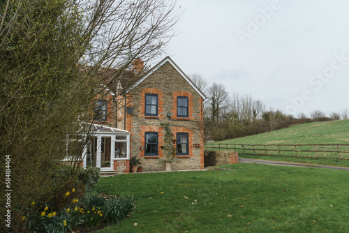 Home Exterior in United Kingdom. Old farmhouse exterior image. Located in England in the Somerset countryside. Contemporary doors and windows in traditional farm house building.