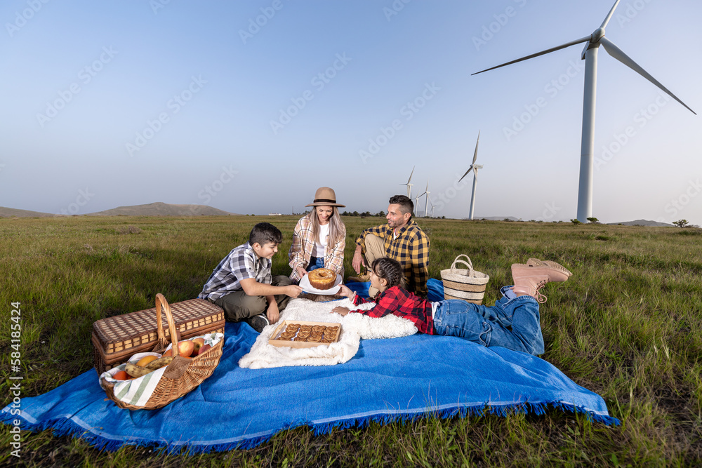 Obraz premium Happy family enjoying picnic in wind farm