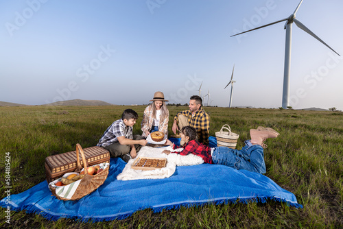 Happy family enjoying picnic in wind farm © Juan Algar