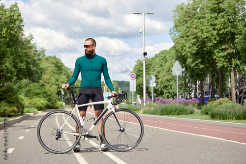 Fototapeta Naklejka Na Ścianę i Meble -  A cyclist man rides a bike in a city park along a bike path.