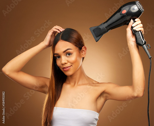 Hair, hairdryer and portrait of woman in studio for growth and color shine or healthy texture. Aesthetic female hands with heat for haircare, self care and hairdresser or salon on brown background