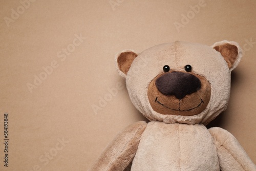Cute teddy bear on brown background, top view. Space for text