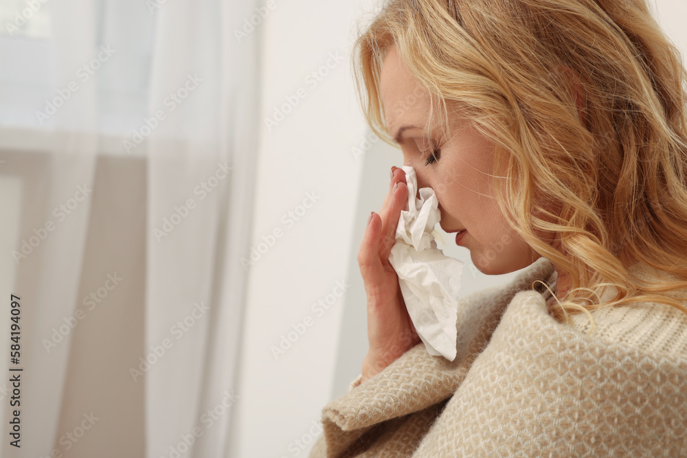 Upset middle aged woman with paper tissue at home, space for text. Loneliness concept