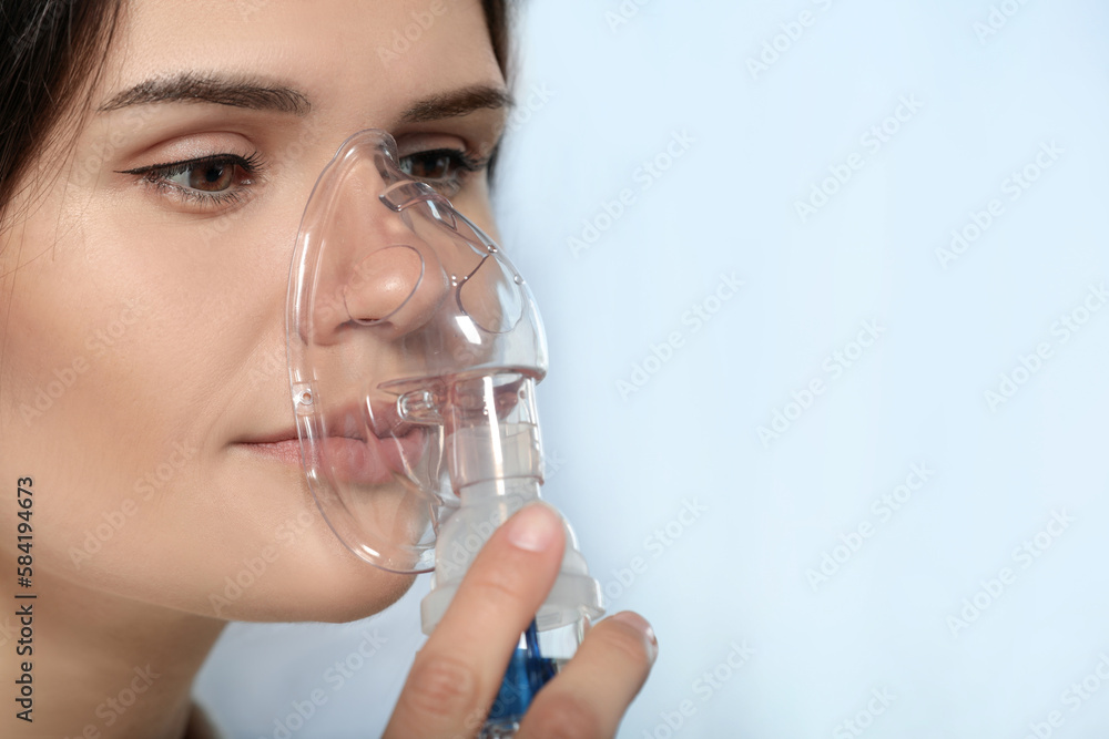 Sick young woman using nebulizer on blurred background, closeup. Space for text Sick young woman using nebulizer on blurred background, closeup. Space for text