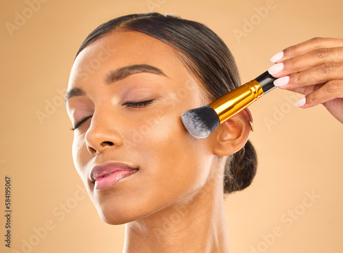 Indian woman, face and makeup, brush and beauty with cosmetic tools and eyes closed on studio background. Skin glow, cosmetology and apply foundation or powder, cosmetics and peace with self care photo