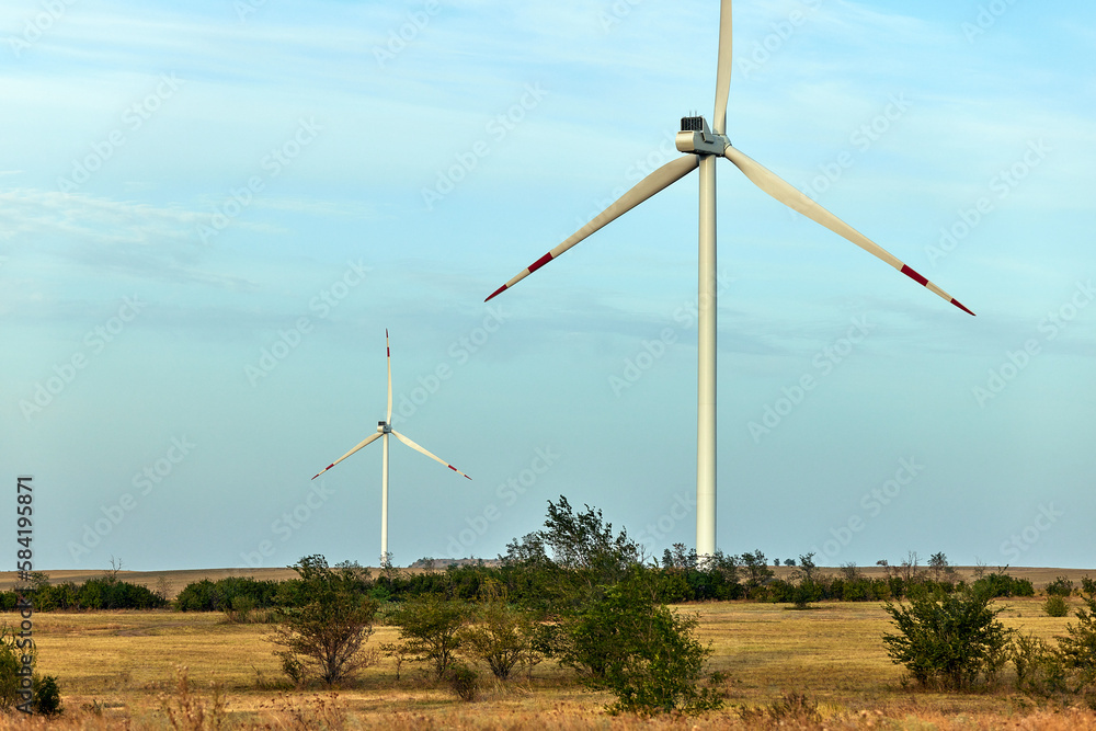 Fototapeta premium Silhouette of wind turbines at sunset. The concept of alternative energy.