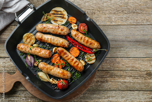 Tasty fresh grilled sausages with vegetables on wooden table, flat lay. Space for text