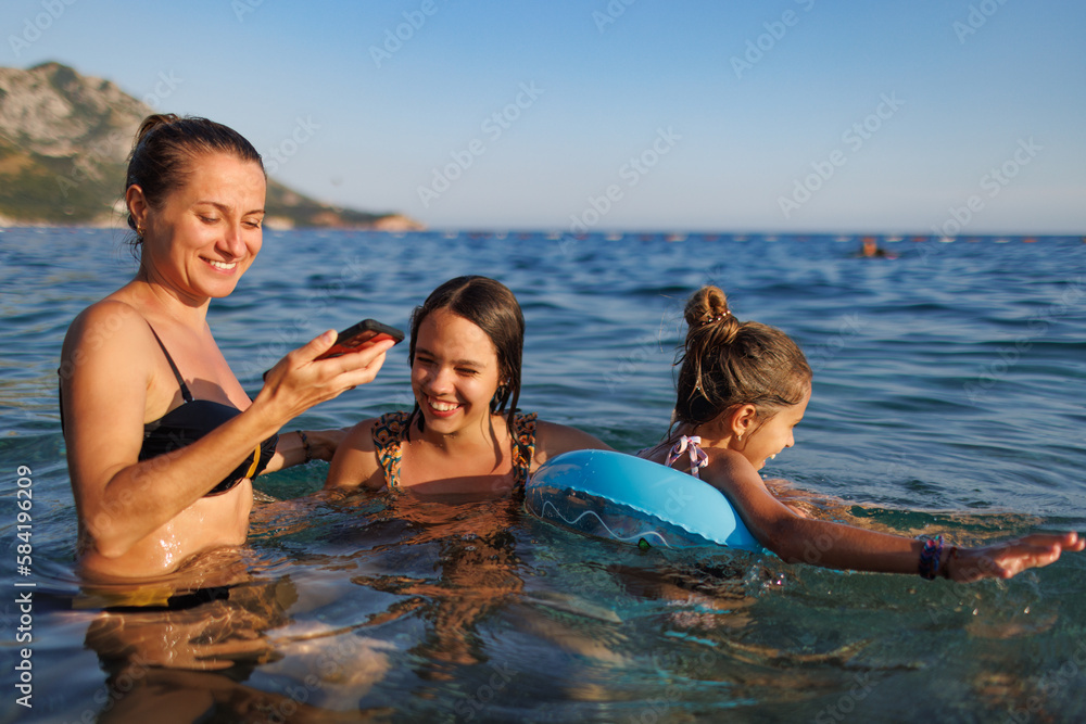 Mom and two daughters take a selfie while swimming in the sea Mom and two daughters take a selfie while swimming in the sea