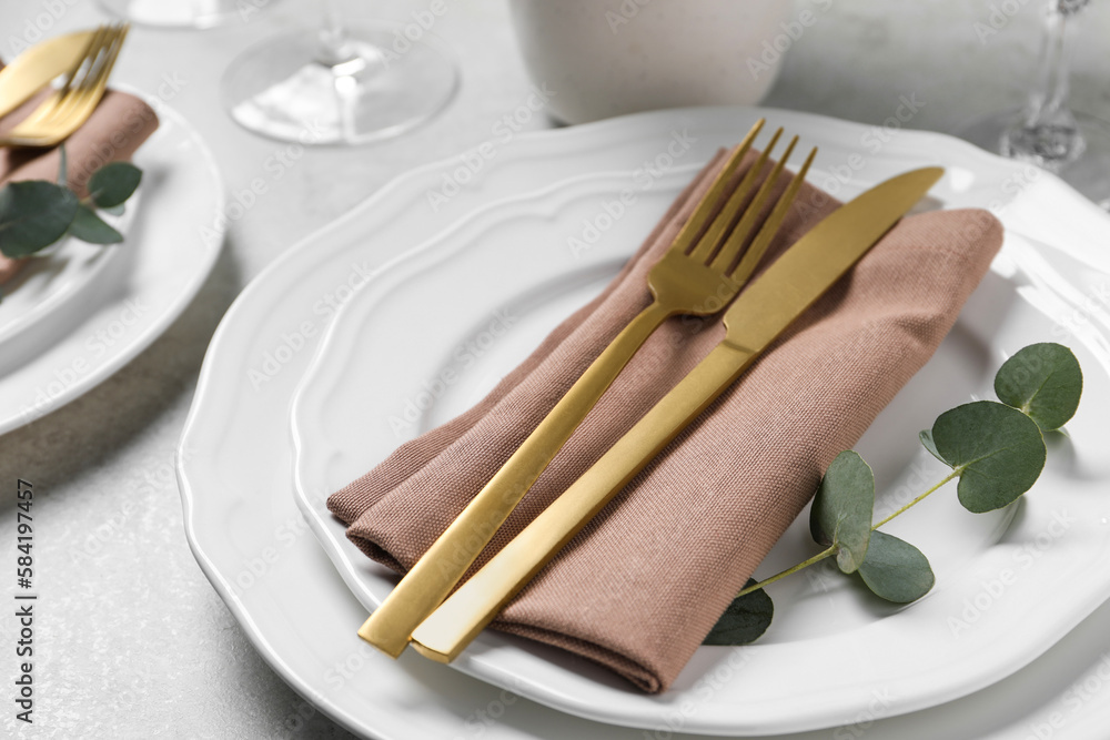 Stylish setting with cutlery and eucalyptus leaves on light grey table, closeup Stylish setting with cutlery and eucalyptus leaves on light grey table, closeup