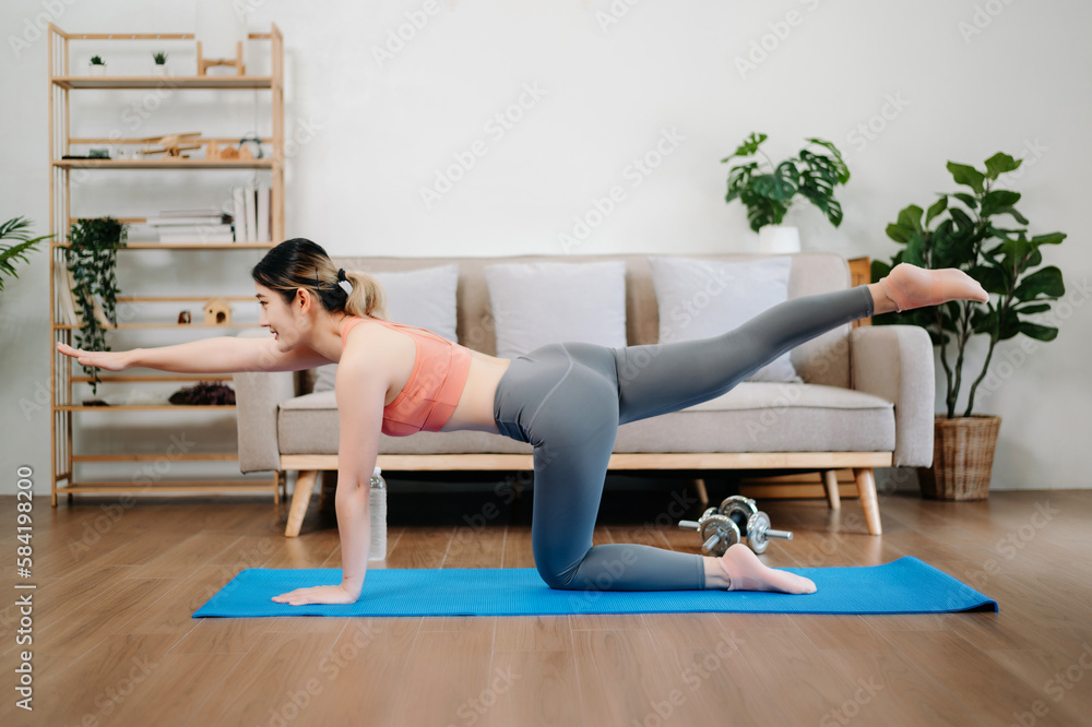 Asian Woman Doing Yoga and Watching Online Tutorials on Laptop, Training in Living Room Asian Woman Doing Yoga and Watching Online Tutorials on Laptop, Training in Living Room