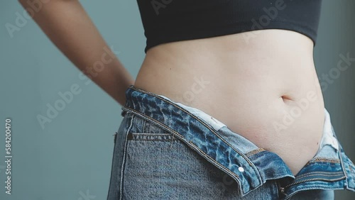 Tummy tuck, flabby skin on a fat belly, plastic surgery concept on gray background